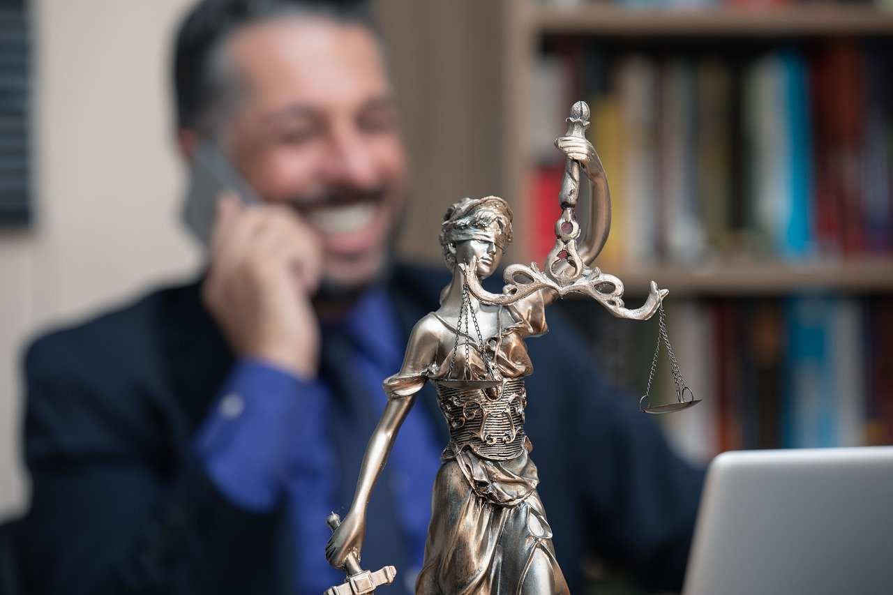Lady Justice statue placed in front of a middle aged man speaking on the phone.